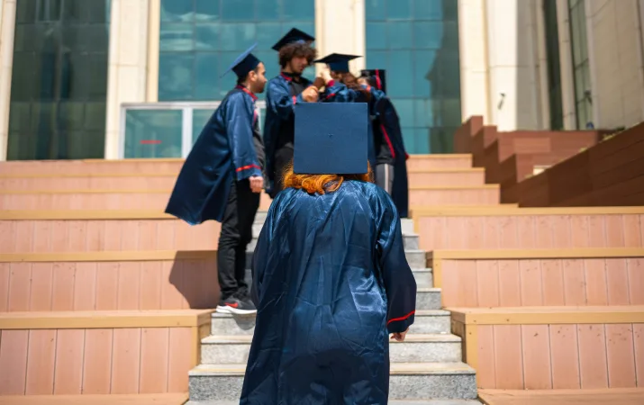 An early childhood teaching graduate proudly walking up the stairs to meet her friends at graduation