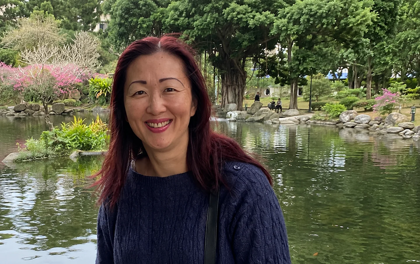 Practising psychologist Catherine Ng standing in front of a tranquil pond