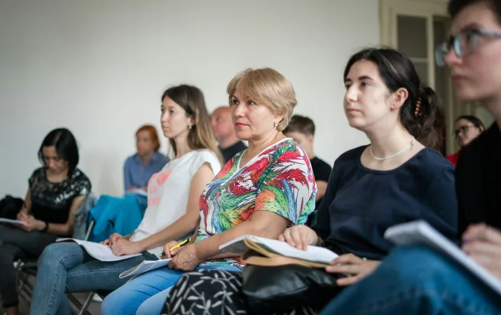 Adults taking notes while attending a group presentation.