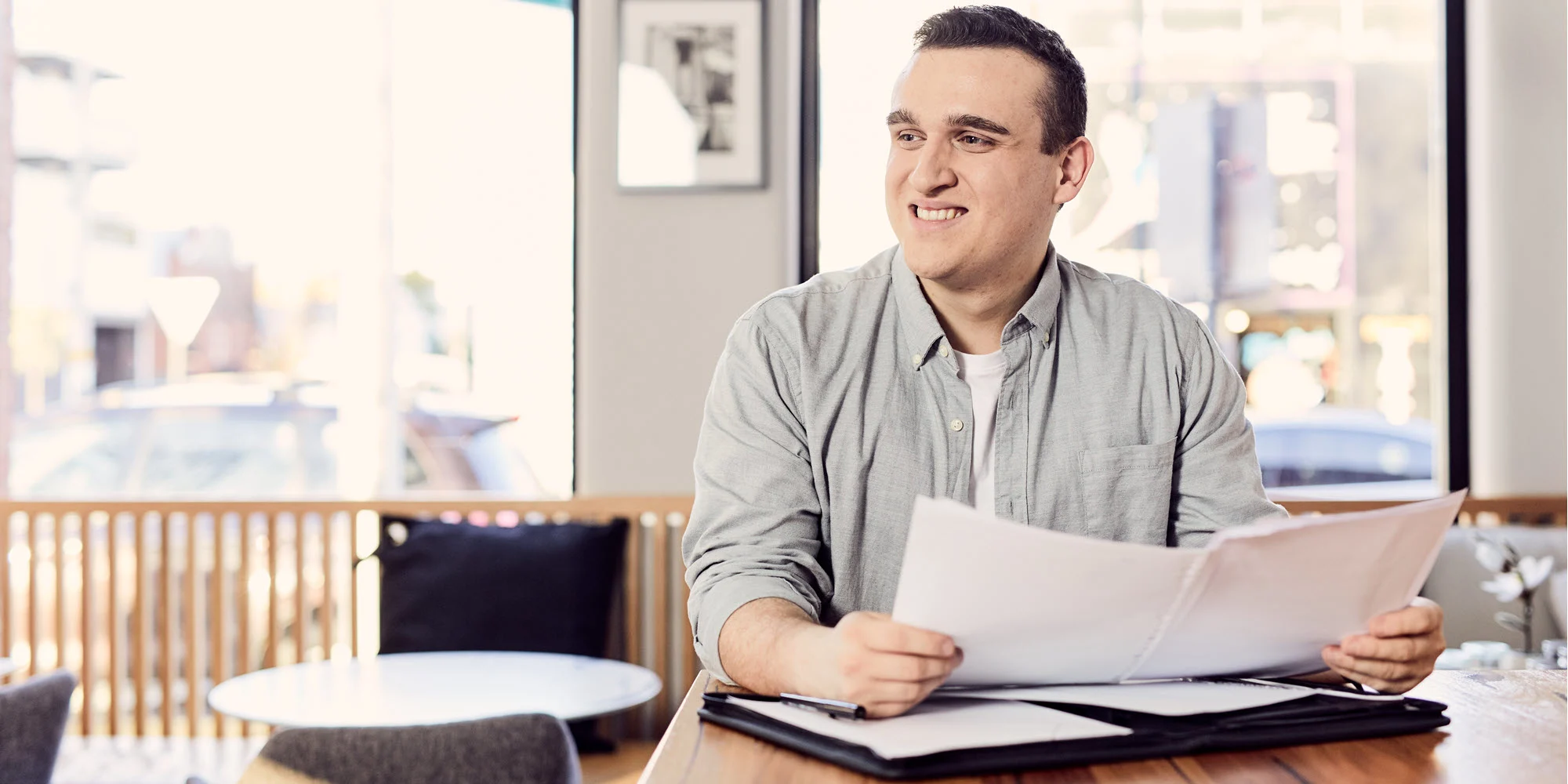 Business graduate reviewing documents in a bright and modern café.