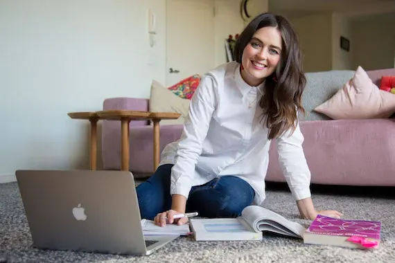 Open Universities Australia student, Nykkea, seated on the lounge room floor with a laptop computer.