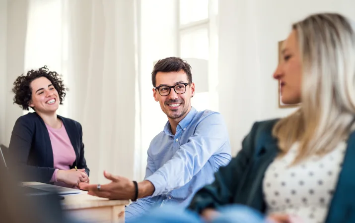 A smiling trio of teachers supporting each other while chatting in the staff room