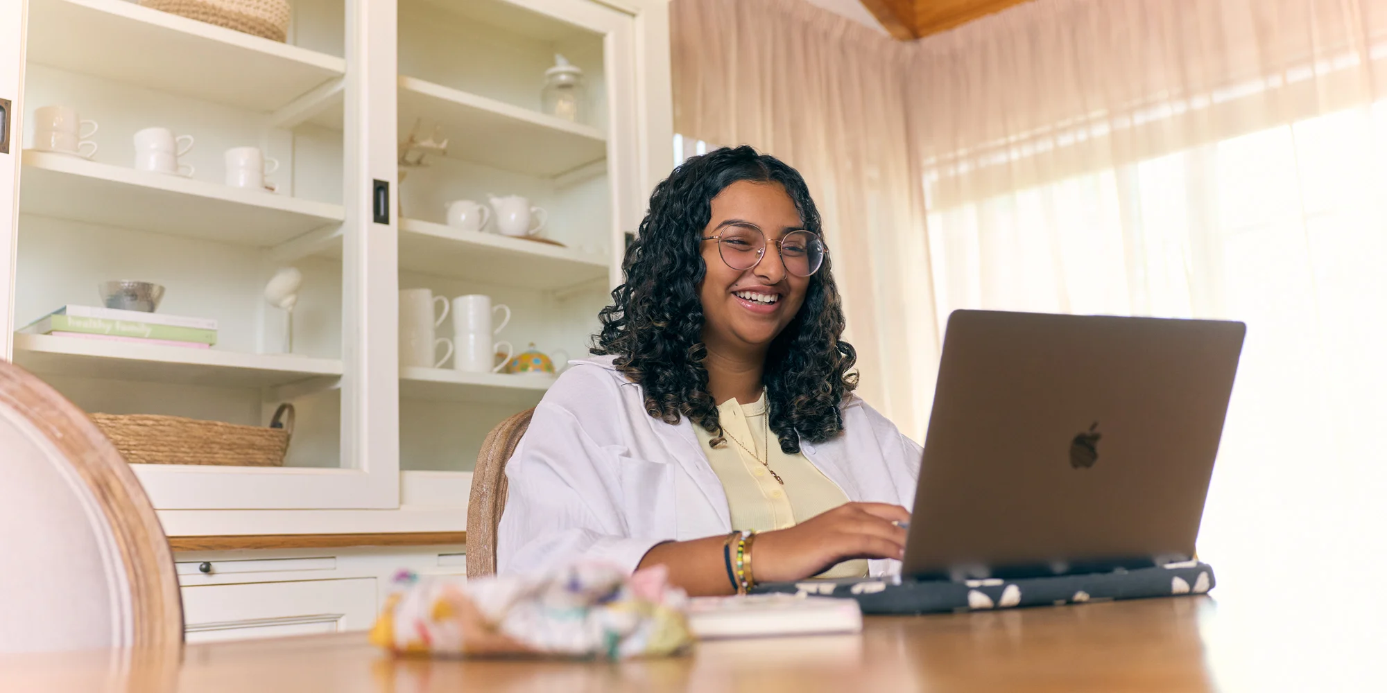 Undergraduate certificate student happily studying from home on her laptop at the dining table.