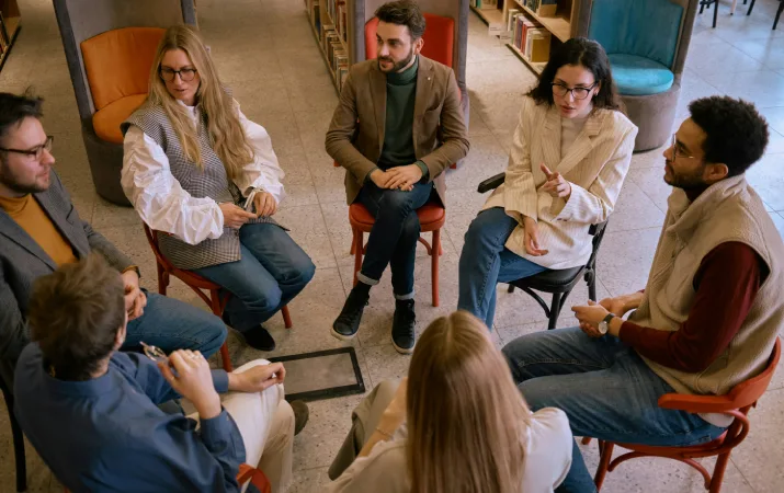 A group of people in a circle in deep discussion during a therapy session
