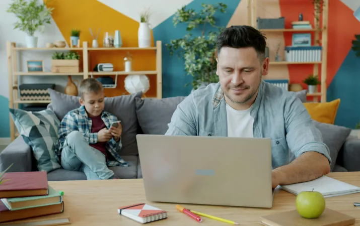 A young dad on his laptop considering his options because he doesn't meet the entry requirements for a psychology course