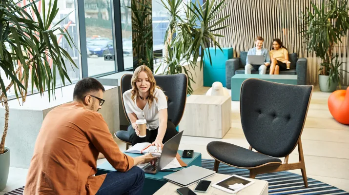 Two content professionals happily chatting about their work in an office