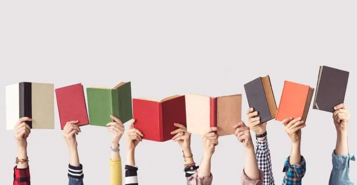 Different peoples' hands playfully holding up a collection of colourful textbooks