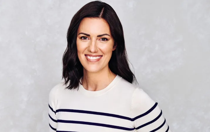 Nicole Maguire smiling in front of a grey backdrop