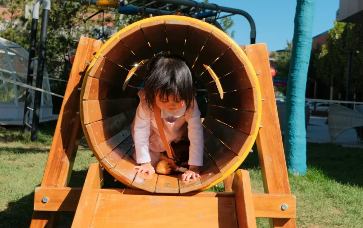 A young child happily playing in a tunnel at a government long daycare centre