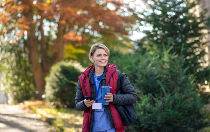 A nurse outdoors on her phone, considering a career change into psychology