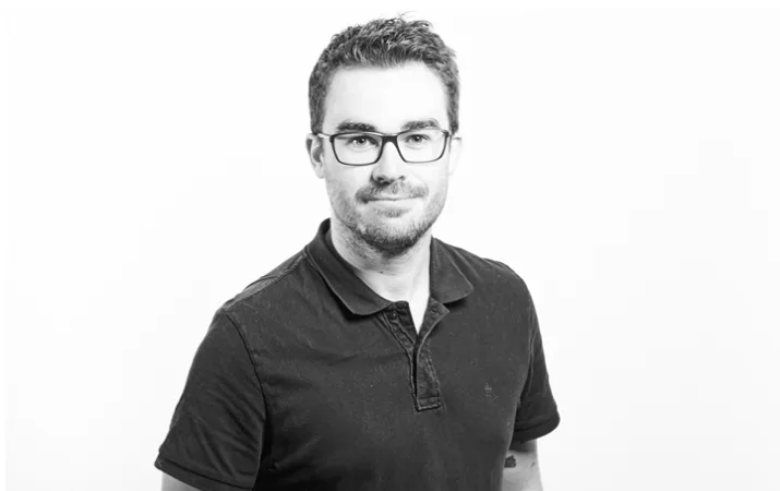 A professional man wearing glasses and a black t-shirt