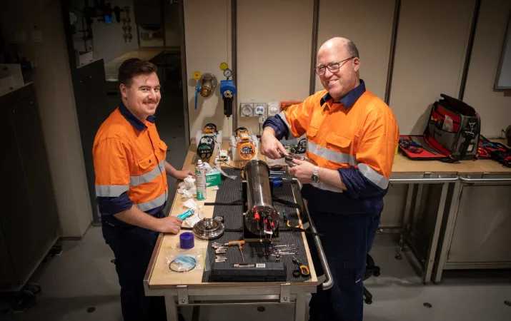Will Rigby and Kym Newbery smiling over a work station covered in equipment
