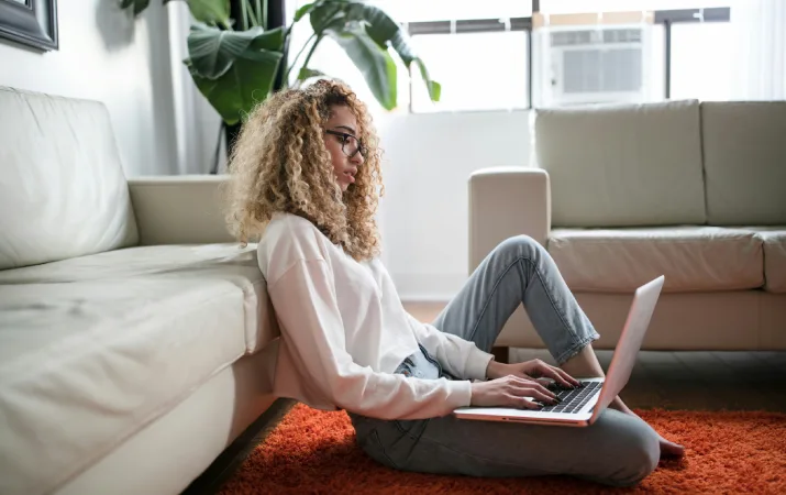 Woman sitting on floor of living room researching study options