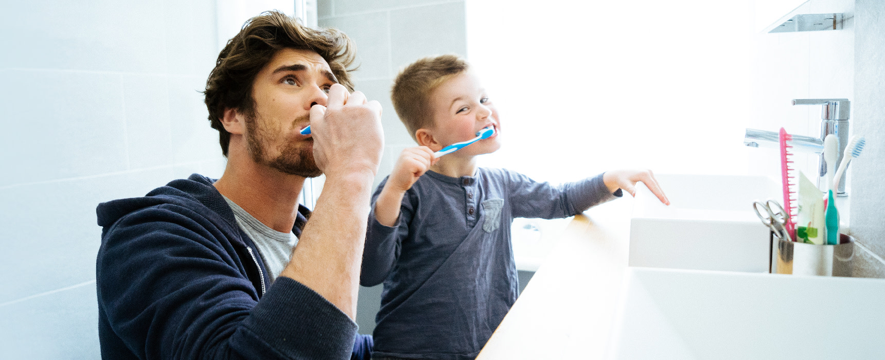 Isä ja poika harjaavat kylpyhuoneessa hampaitaan.