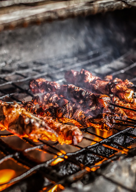 Pork skewers cooking over hot charcoal