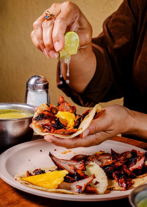 Perfecty charred al pastor tacos with pineapple and a squeeze of lime