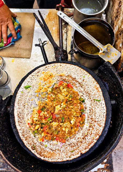 Paneer masala dosa sizzling on a cast iron griddle.