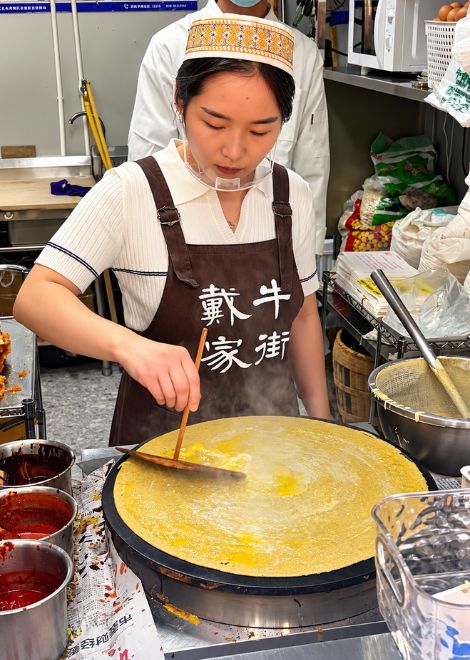 Jianbing batter spread thin across a sizzling griddle.