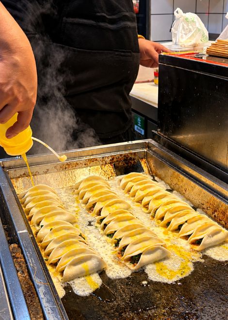 Dumplings crisping up on a hot griddle along Ox Street.