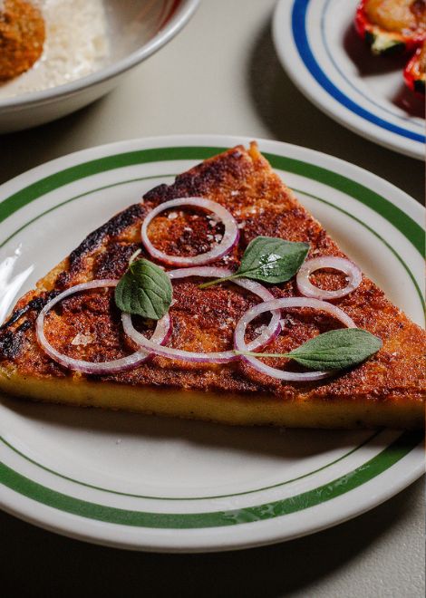 Crisp-edged fainá topped with sweet onions and smoky paprika