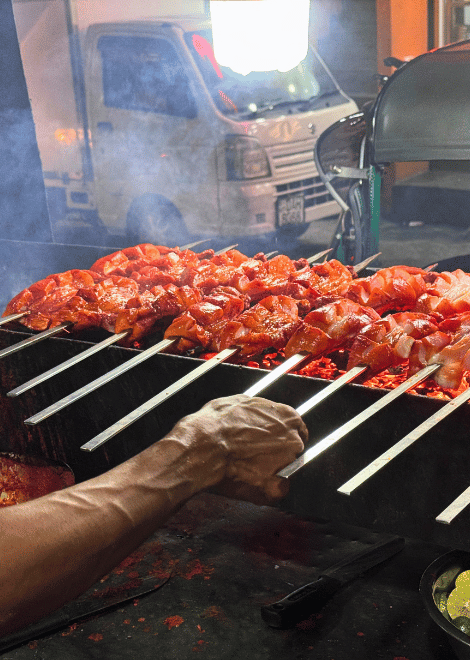 Masala-spiked chicken sizzling over glowing charcoal.
