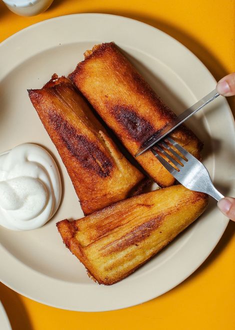 Crispy tamal de elote frito topped with rich Salvadoran crema.