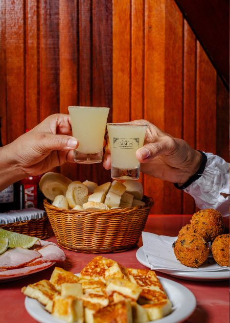 Sliced pork picanha, grilled queijo coalho, and crispy cod fritters paired with a glass of cachaça