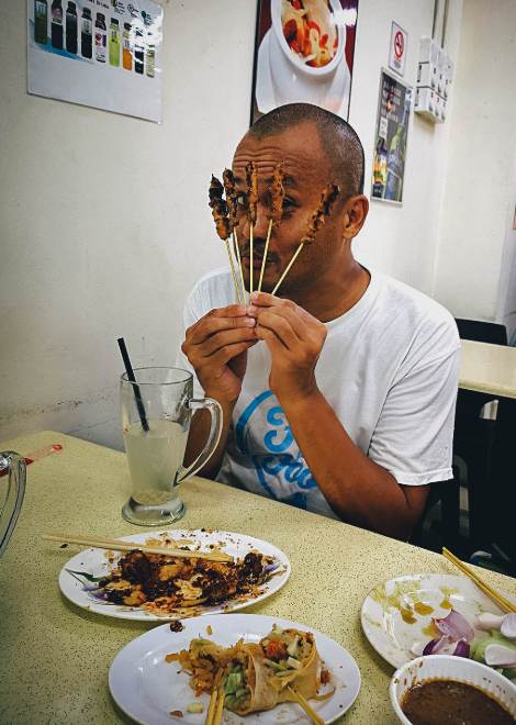 Eating barbecued chicken with rich satay sauce