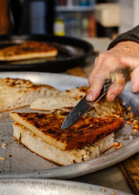 A classic Porteño pairing: chickpea fainá served alongside onion-topped fugazza fresh from the oven