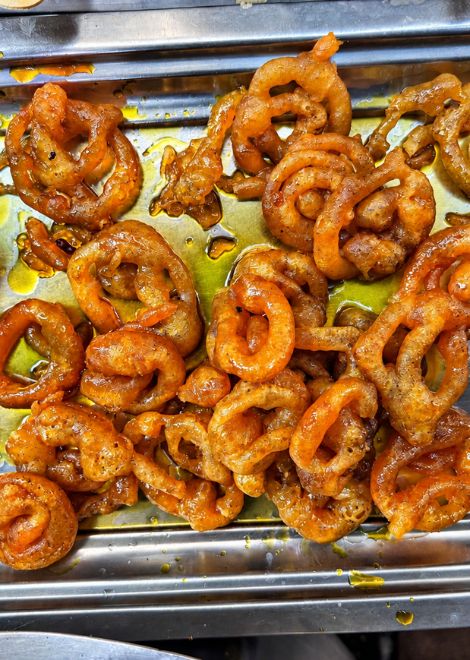 Sticky, syrup-soaked jalebi glistening on the tray.