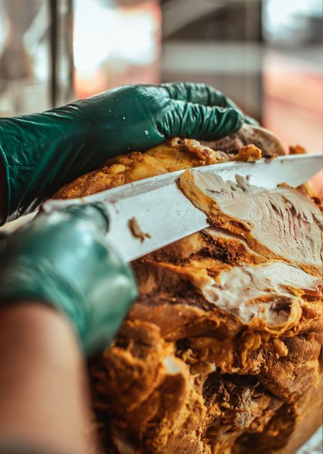 A skilled hand slices tender pork for a traditional butifarra