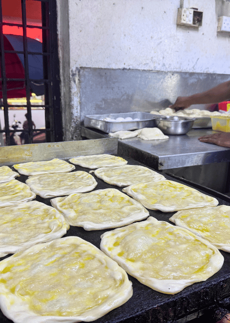 Fresh parathas hitting the griddle, stuffed with melting cheese.