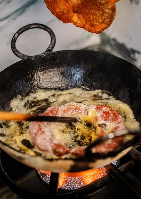 Freshly fried picarones emerge golden and crisp from the bubbling oil