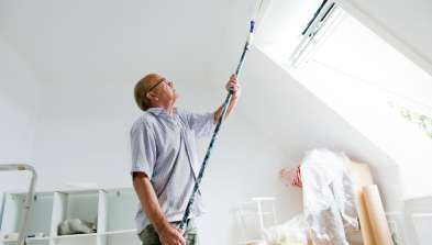 Man painting attic room next to skylight