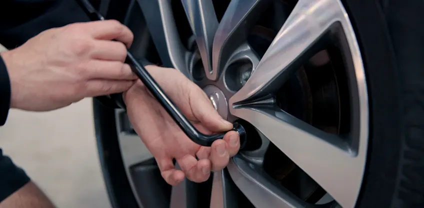 Loosening wheel nuts with a wheel brace.