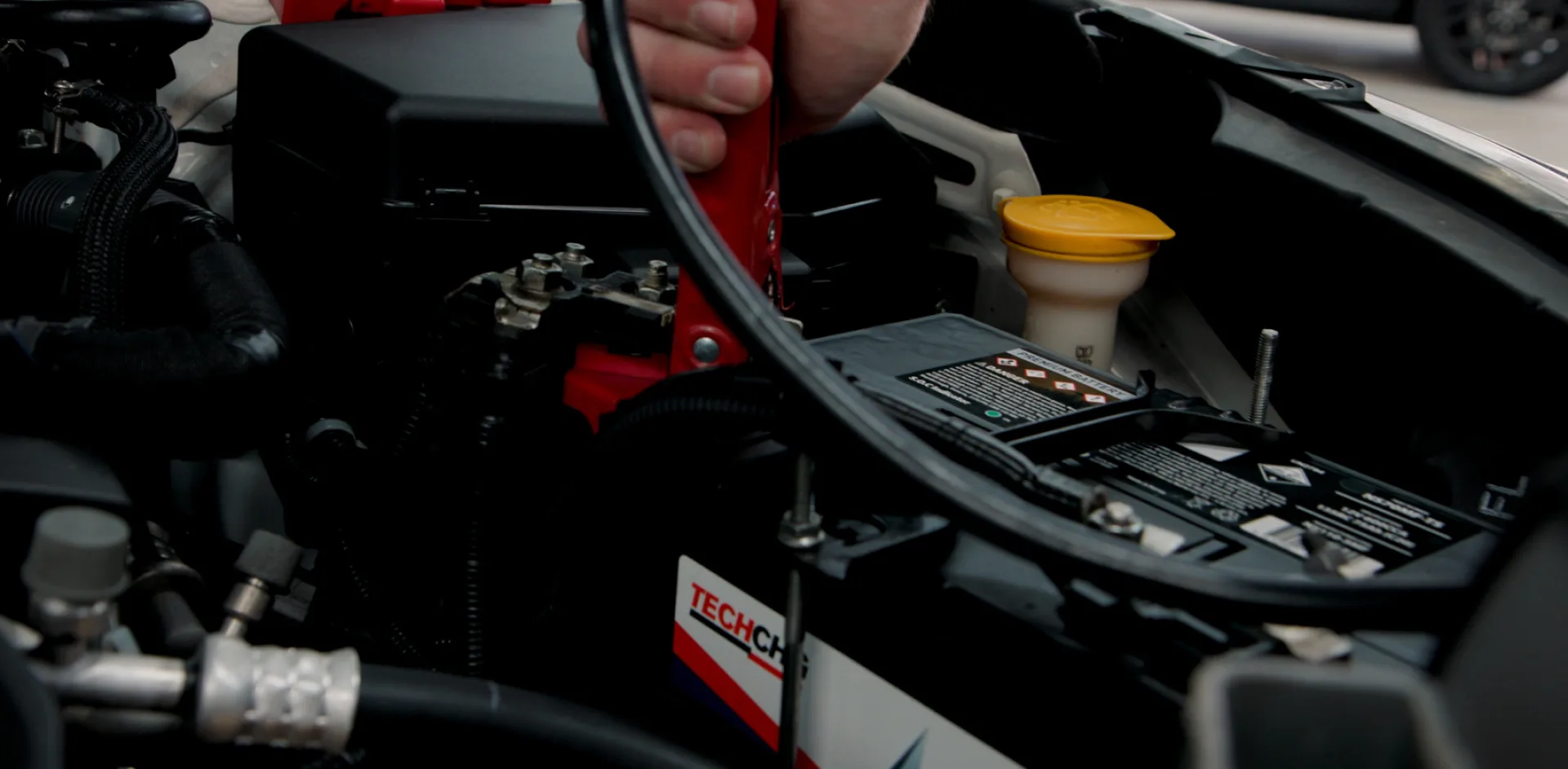 Attaching the positive jumper lead to the positive terminal of the flat battery.