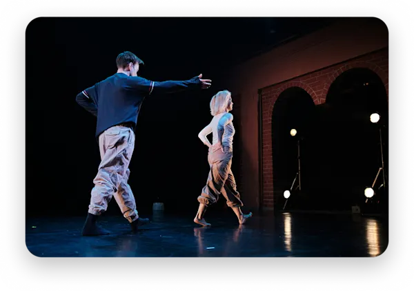 Two dancers mid-performance under stage lights