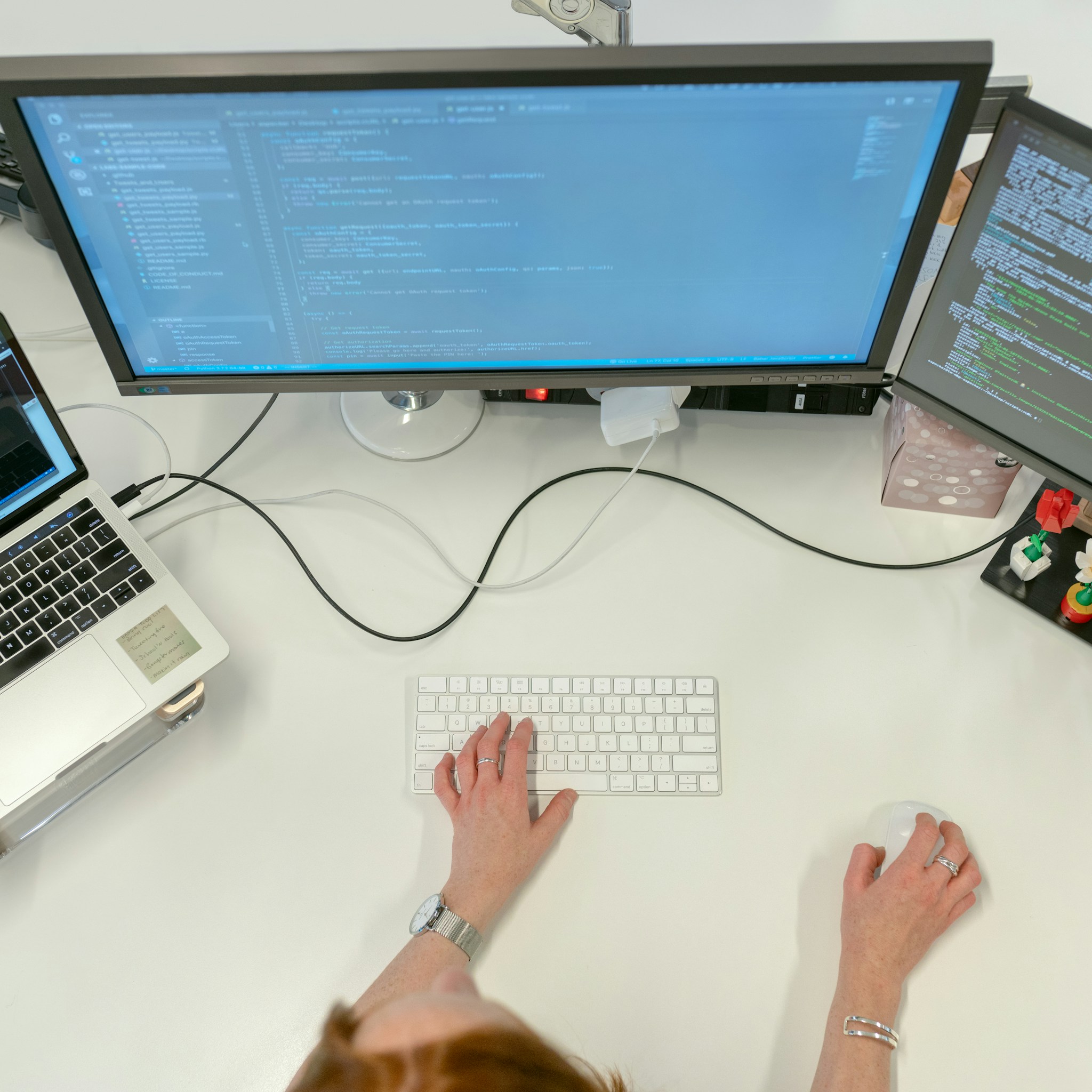 Software engineer working on multiple computer screens in a modern office.