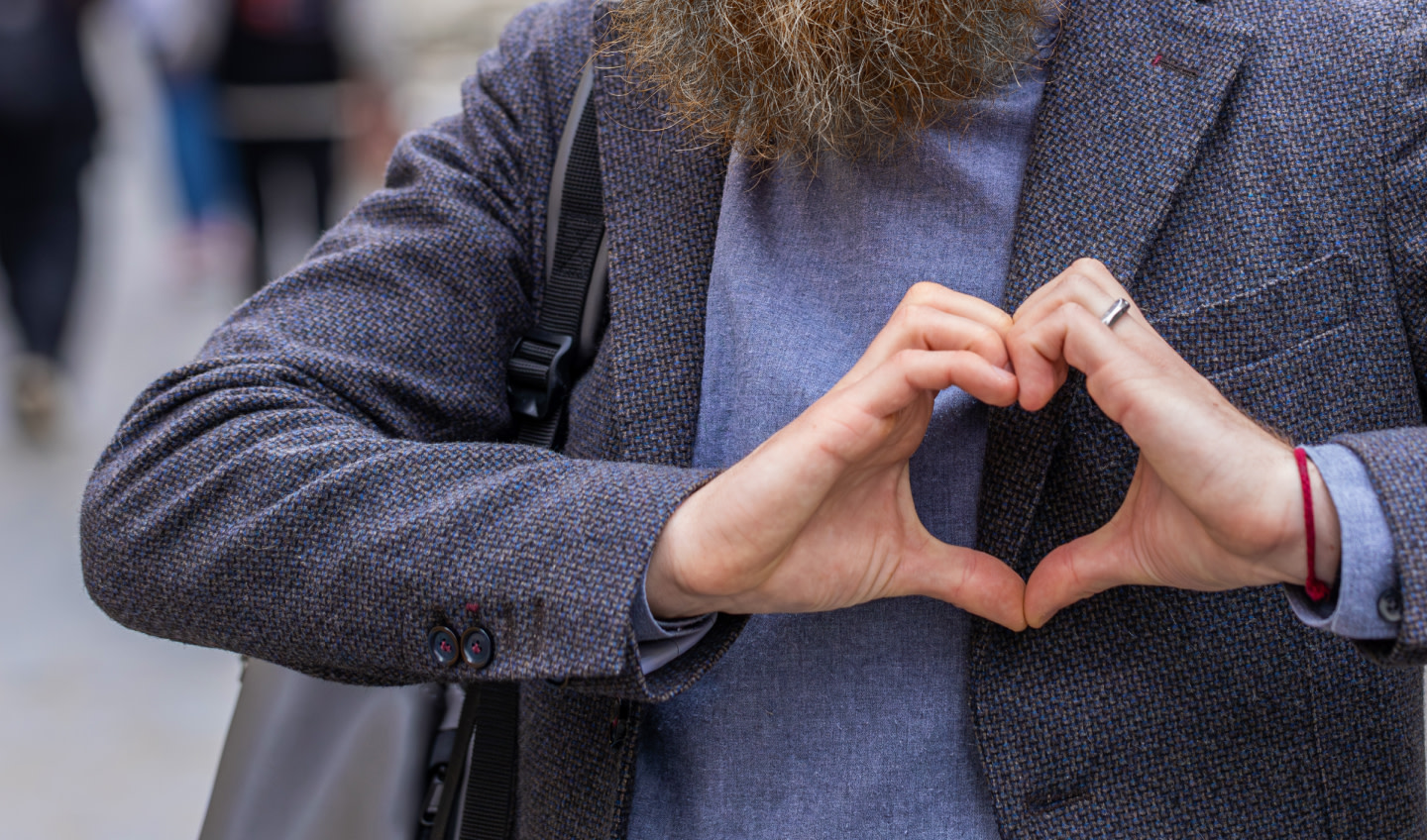 Hands making the shape of a heart over man’s chest.
