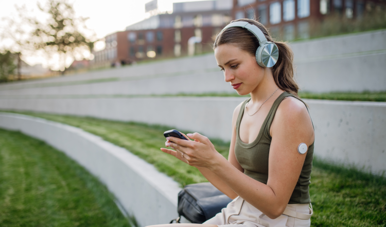 A person with a wearable health technology piece on her arm using an app on a mobile phone.