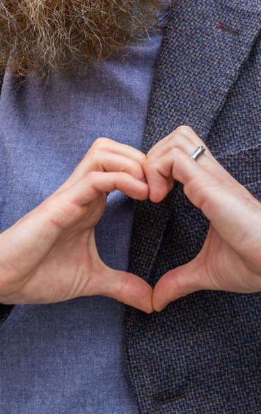 Hands making the shape of a heart over man’s chest.