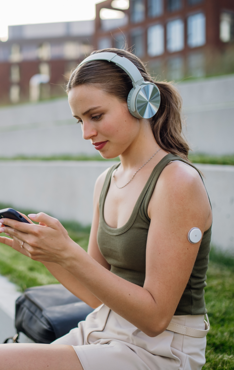 A person with a wearable health technology piece on her arm using an app on a mobile phone.