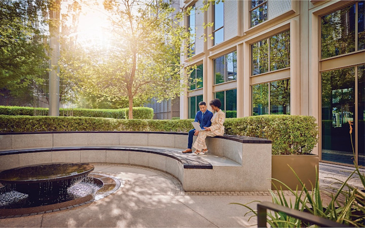 offices-gallery-1 man and woman sitting at a staired-bench smiling while working on a laptop