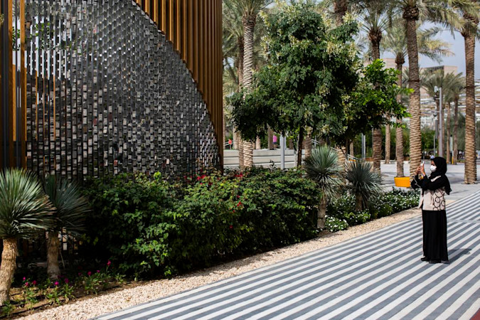 Woman taking a photo of the structures in the park from a pathway