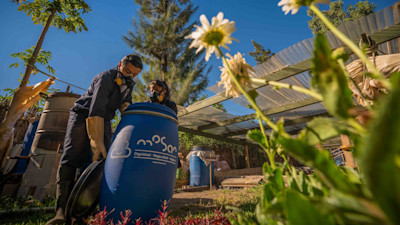 Two workers opening a blue-colored barrel with Mosan's logo on it