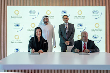Her Excellency Reem Al Hashimy and His Excellency Sunjay Sudhir signing an agreement while His Highness Sheikh Ahmed bin Saeed Al Maktoum and Professor Rakesh Mohan Joshi standing behind.