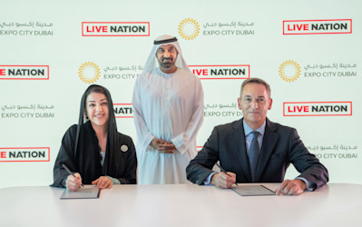 Her Excellency Reem Al Hashimy and James Craven – President, Live Nation Middle East signing agreement while His Highness Sheikh Ahmed bin Saeed Al Maktoum standing in the back.