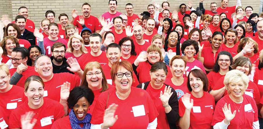 large group of Lilly volunteers wearing red shirts waving at the camera