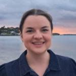 Woman smiling by water at sunset