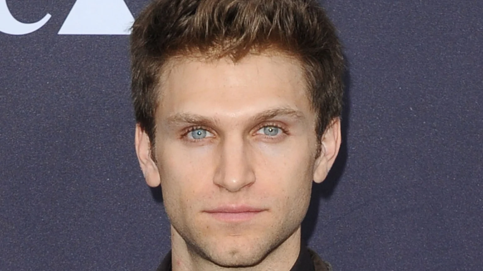 A close-up headshot of Keegan Allen, a young man with light blue eyes, short brown hair, and light skin, looking directly at the camera.